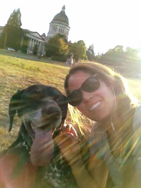 Karla with her dog laying in the grass in front of the Capitol Building in Washington State