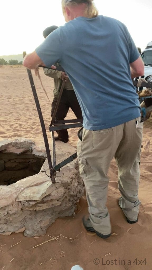 Brett and the camel herder beginning to restore the safety structure on a desert well after rescuing a baby camel in Morocco