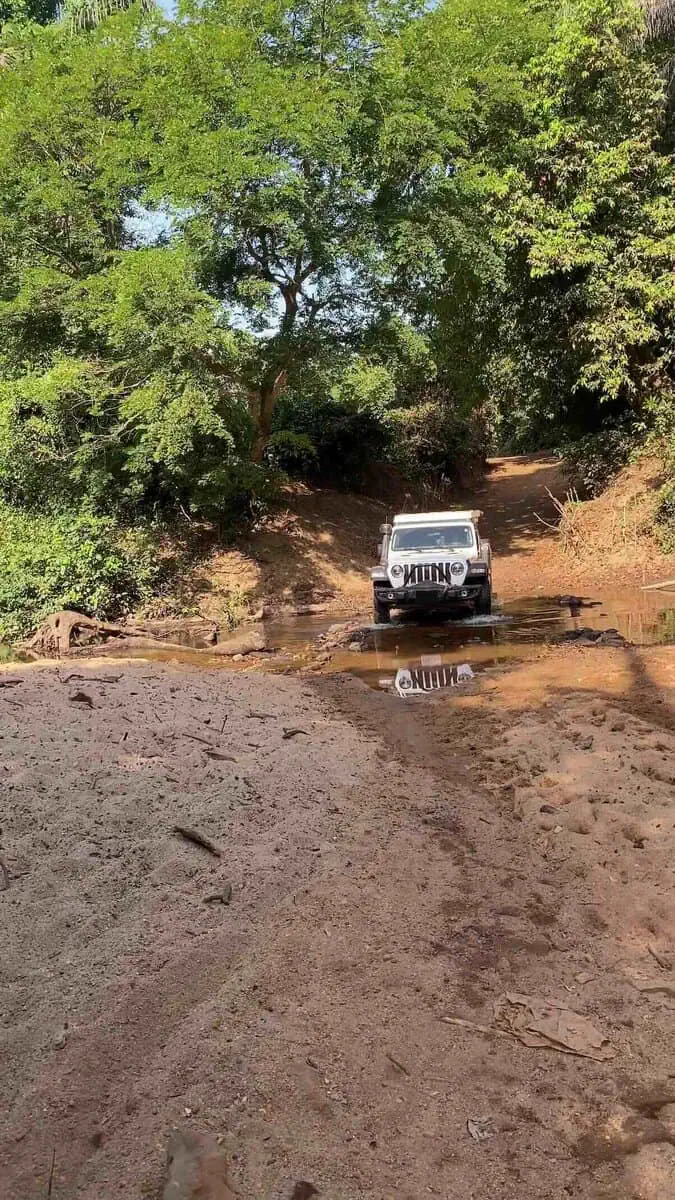 Jeep Wrangler Rubicon crossing small creek on dirt road in Guinea during overland Africa trip