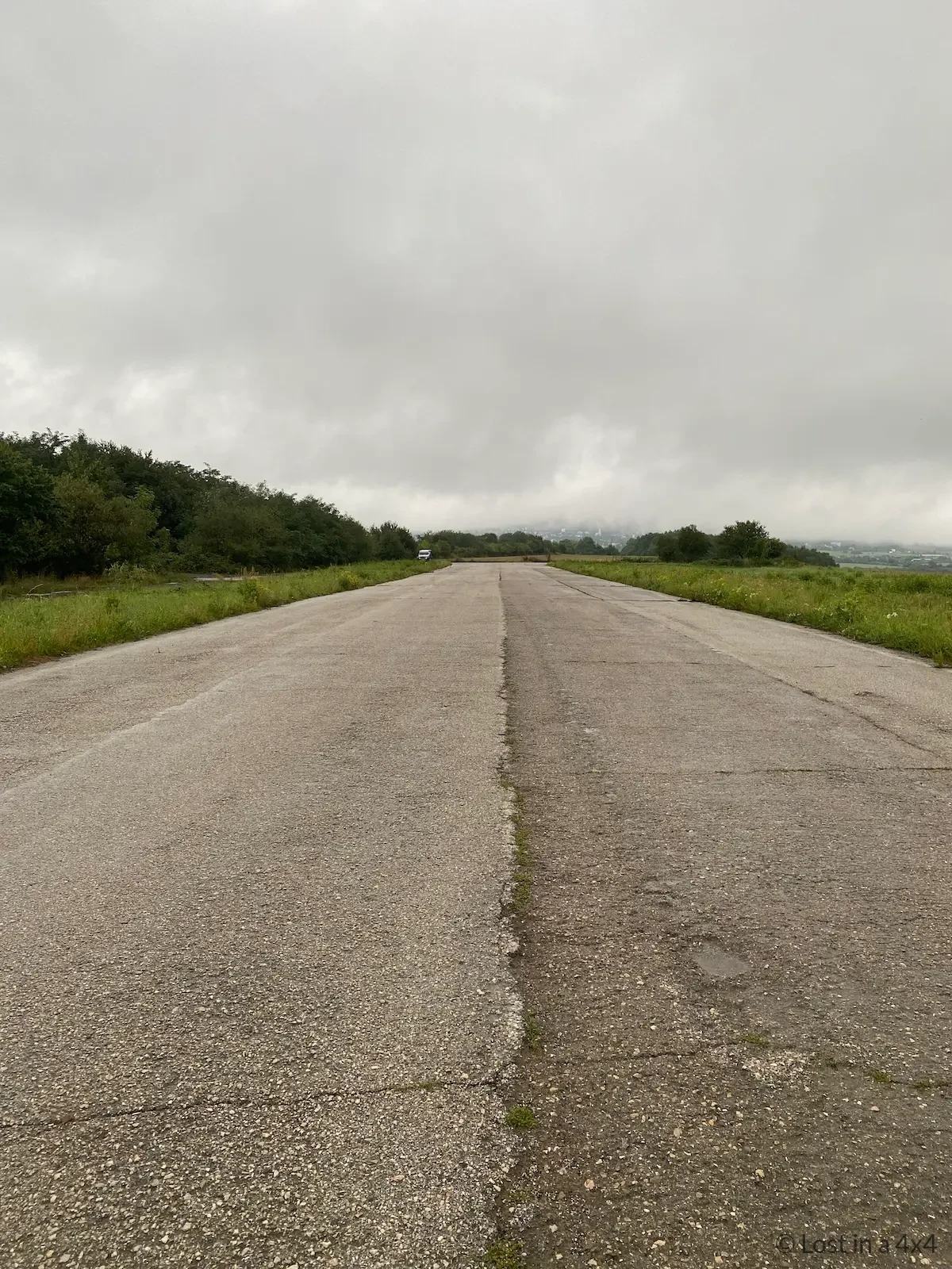 Abandoned runway in Slovakia with a lone Jeep parked in the distance during wild camping, illustrating isolation and fear while overlanding the world.