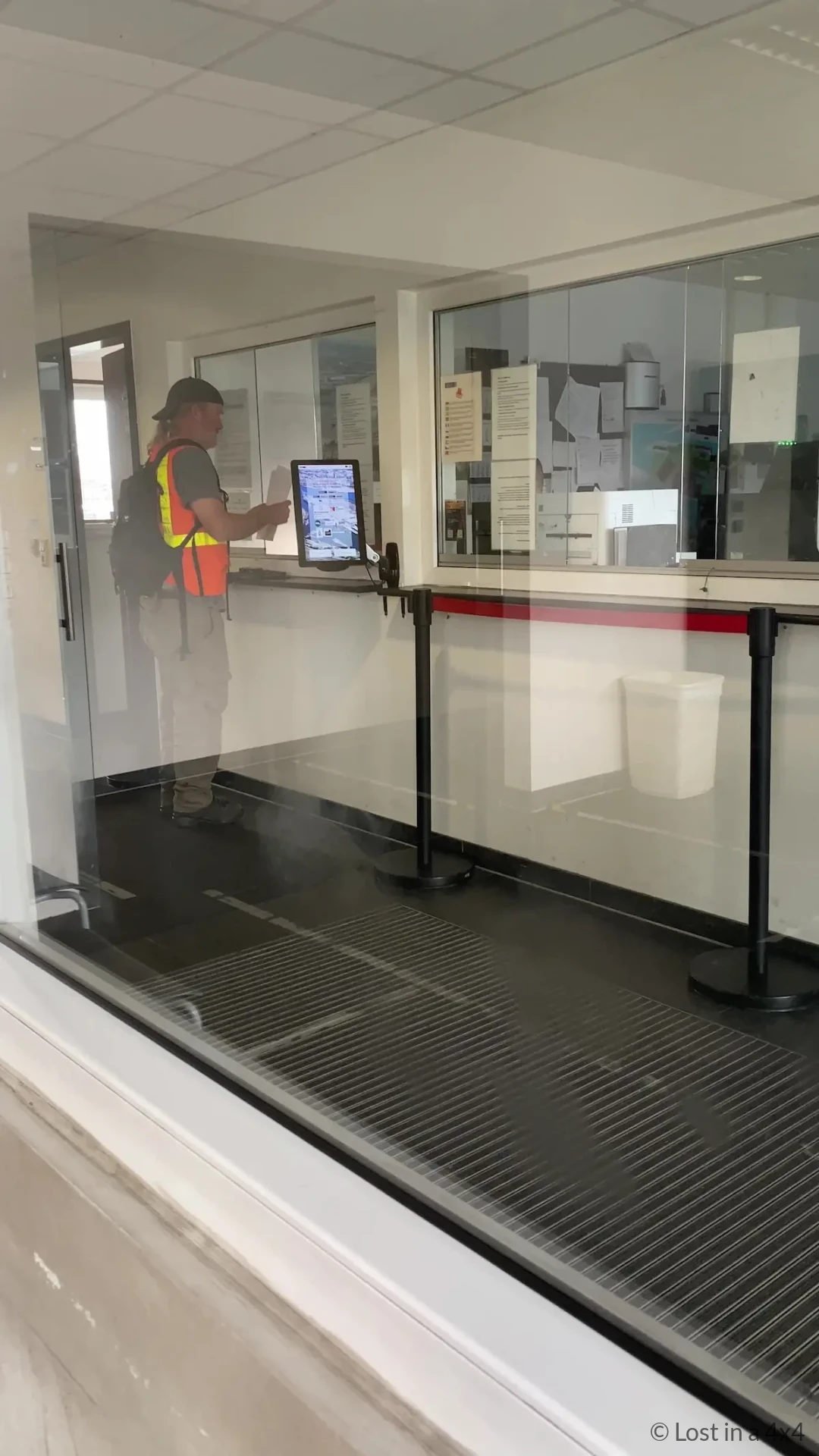 Brett wearing high visibility vest at Unikai port office window collecting map to locate Jeep in Hamburg port