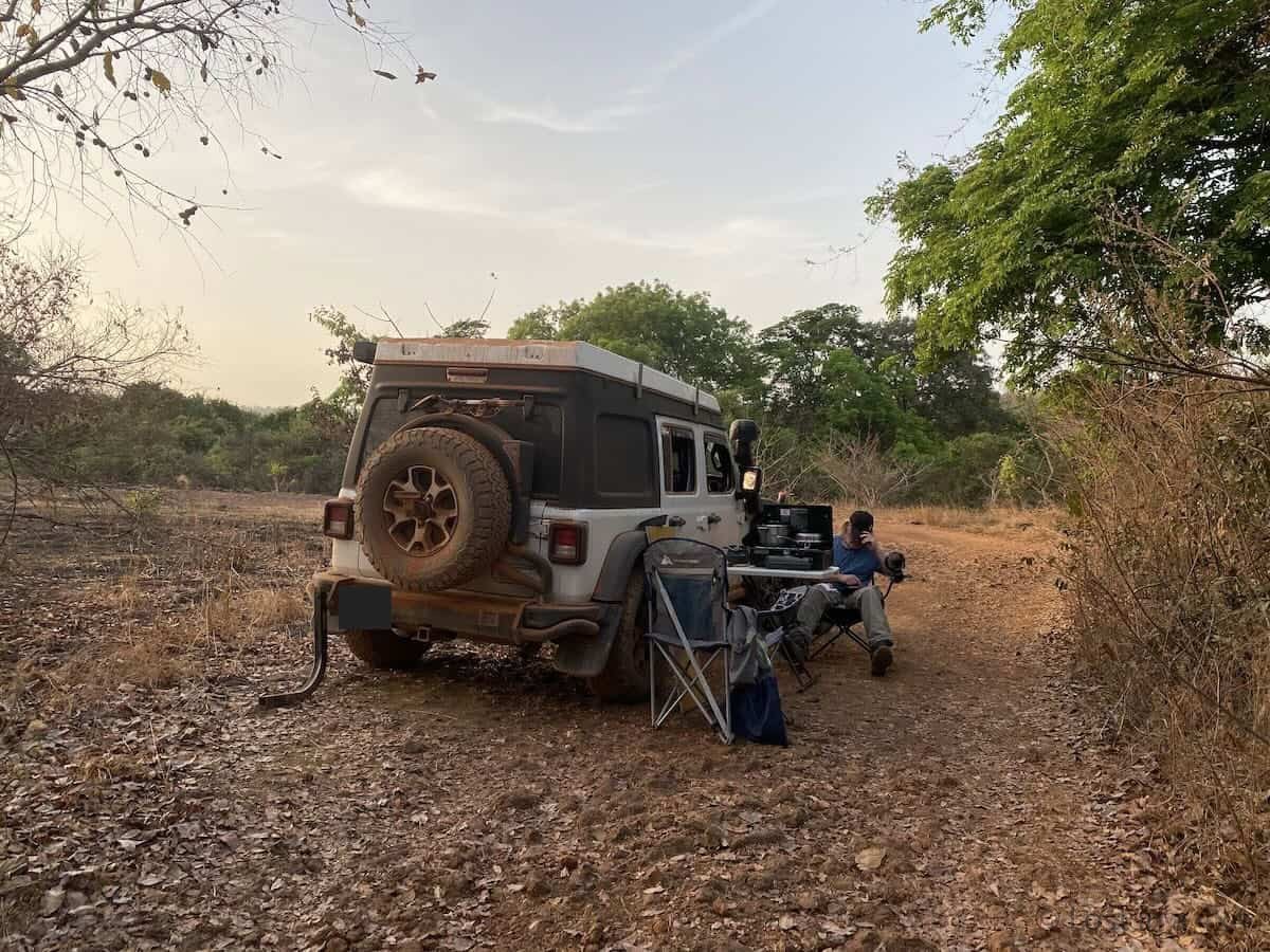 Brett sitting in a camping chair beside a cooking stove at a wild camp on our way to Les Échelles de Djinkan in Guinea