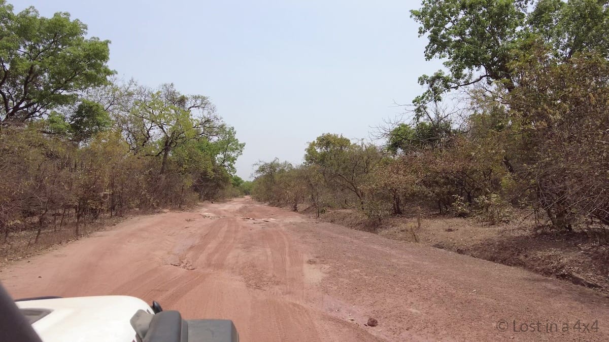 Jeep Wrangler driving on a rough dirt road in Guinea near the border with Guinea-Bissau during an overland journey through West Africa.