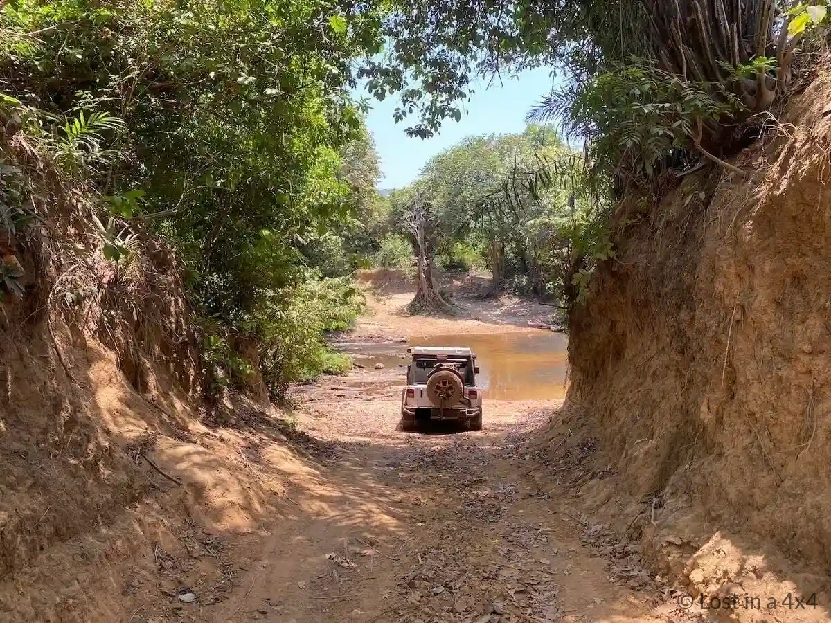 Jeep Wrangler Rubicon at edge of small creek on hill in Guinea before crossing during overland Africa trip