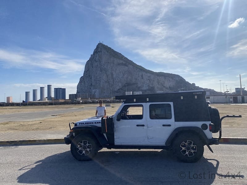 Karla standing behind the Jeep in Spain with Gibraltar Rock in the background during an overland journey with Lost in a 4x4