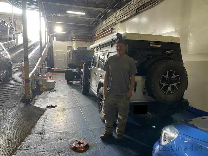 Brett standing next to a Jeep parked inside the ferry during the crossing from Spain to Morocco