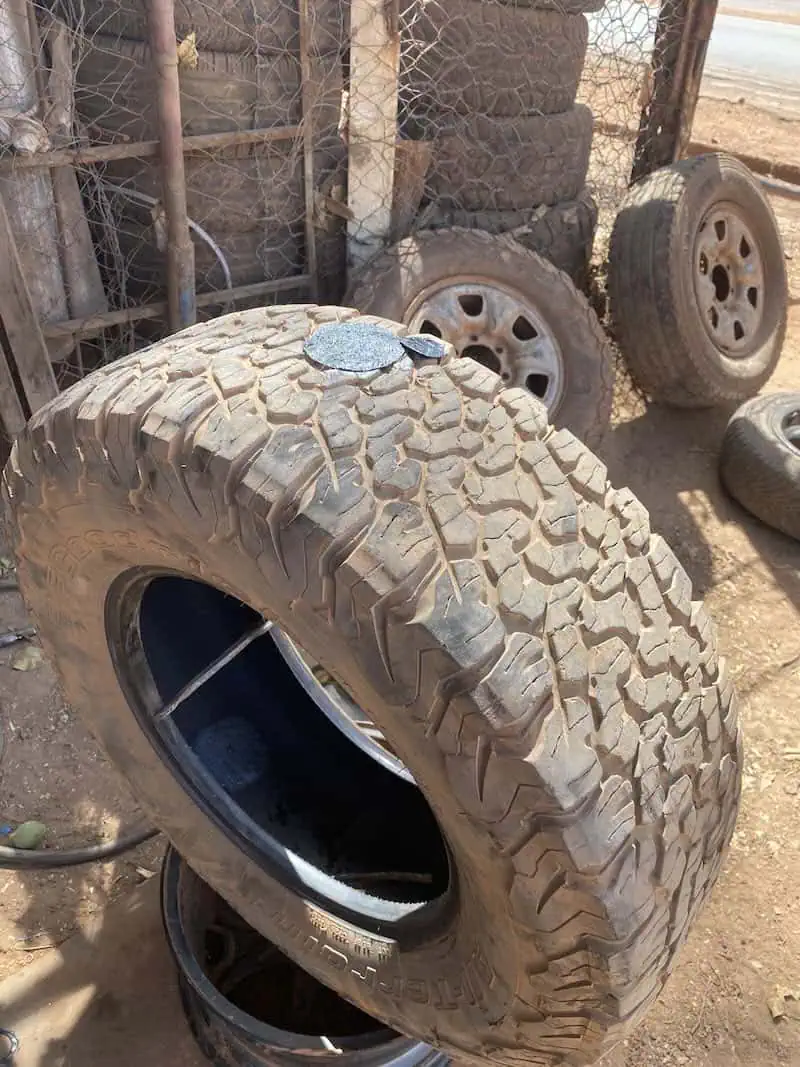 Tire patches drying with glue during Jeep overland tire repair in Guinea.