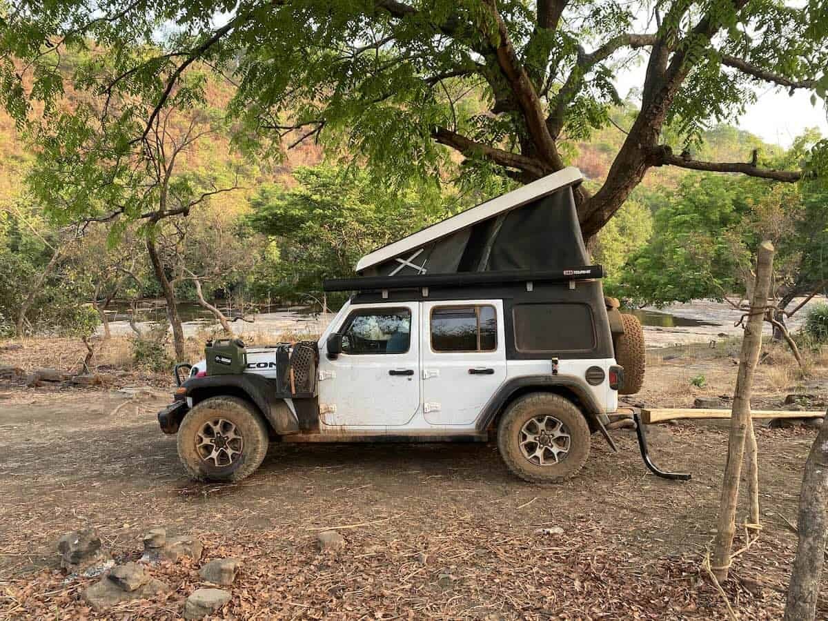 Jeep Wrangler Rubicon with Ursa Minor rooftop tent wild camping near Kambadaga Waterfall river in Guinea.