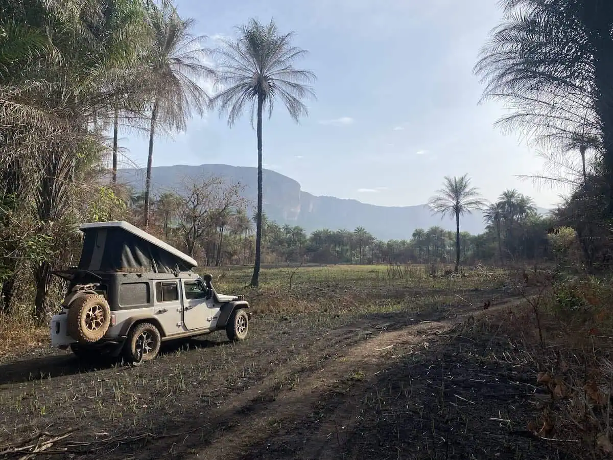 Jeep Wrangler Rubicon with Ursa Minor rooftop tent set up at wild camp overlooking sheer cliff mountains in Guinea