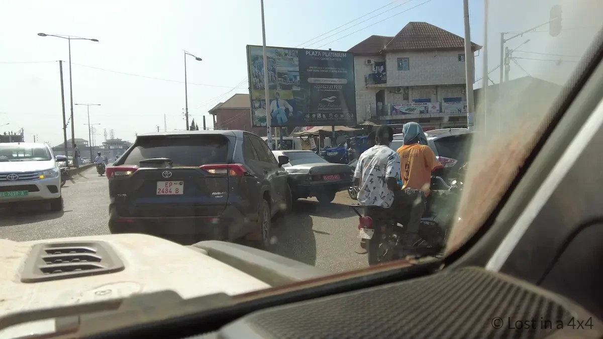 View from inside a Jeep Wrangler windshield showing a vehicle collision on the road in Conakry, Guinea during traffic