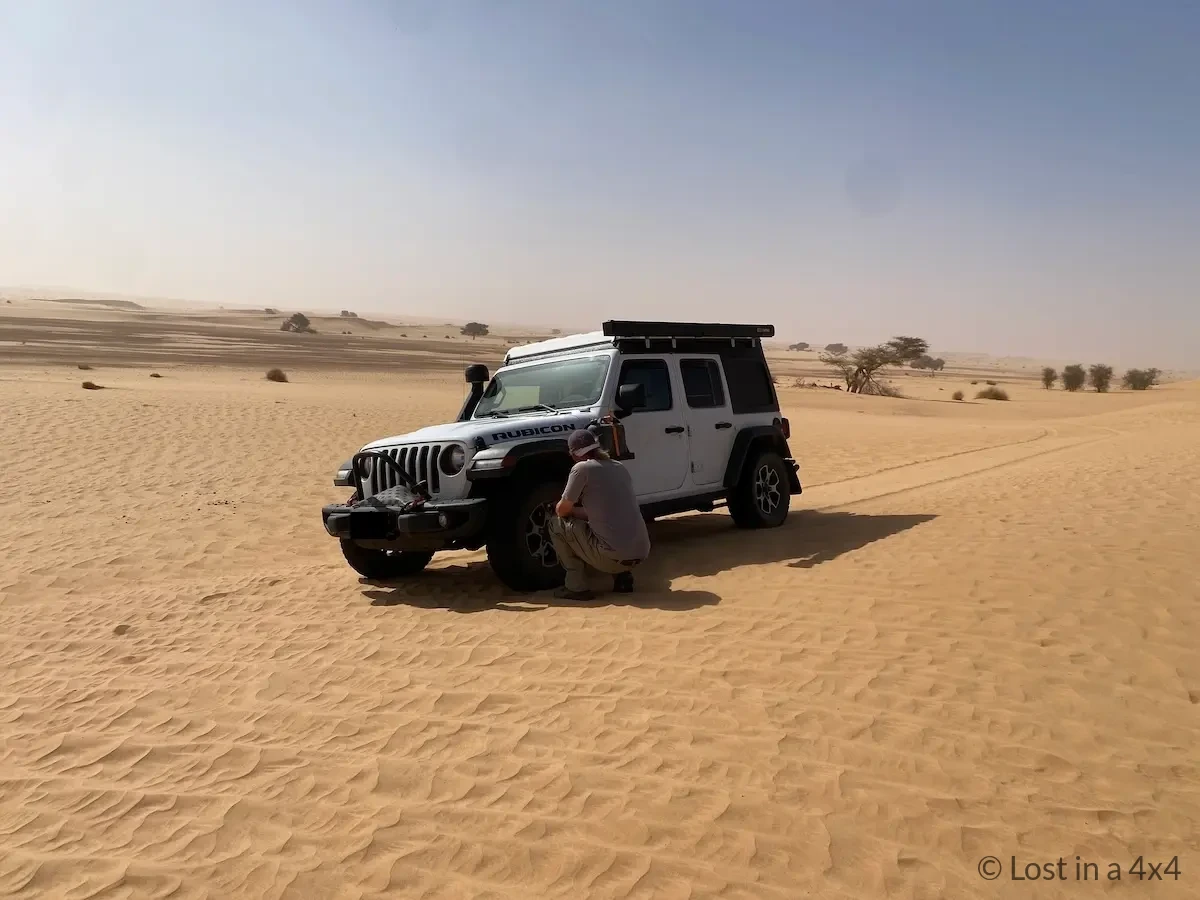 Jeep Wrangler in the Sahara Desert in Mauritania with tires deflated for traction while traveling to the Eye of Africa, illustrating vehicle breakdown and recovery during overlanding.