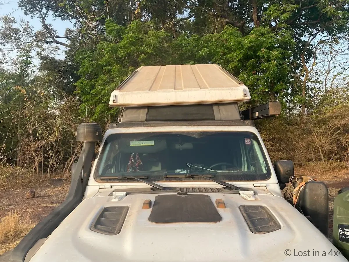Front view of Jeep Wrangler with white Ursa Minor pop-top roof at a wild camp in Guinea showing heat-reflective design.