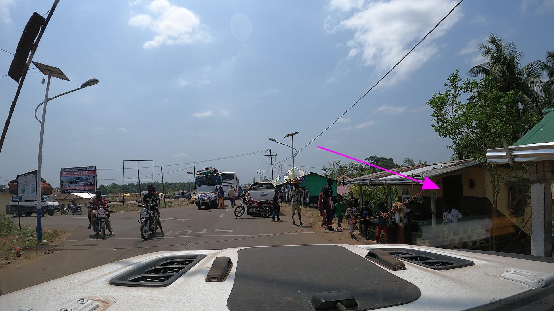 Jeep Wrangler parked at the Liberia border roadblock beside the passport and visa control office during overland travel through Africa.