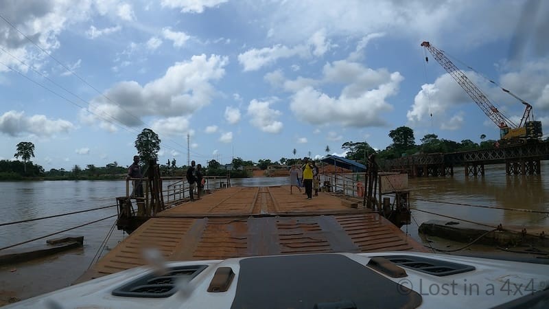 View from inside a Jeep Wrangler driving onto the ferry crossing the Cavalla River between Liberia and Côte d’Ivoire during overland travel.