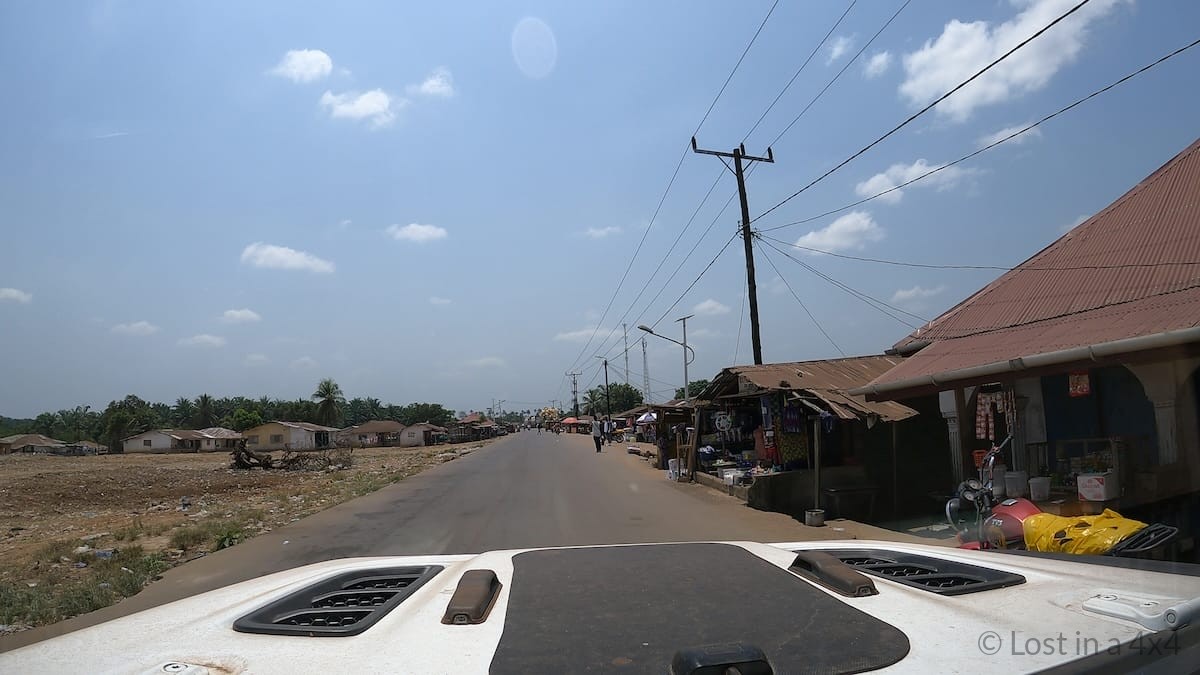 Jeep Wrangler driving on a paved road in Liberia showing road conditions during overland travel.