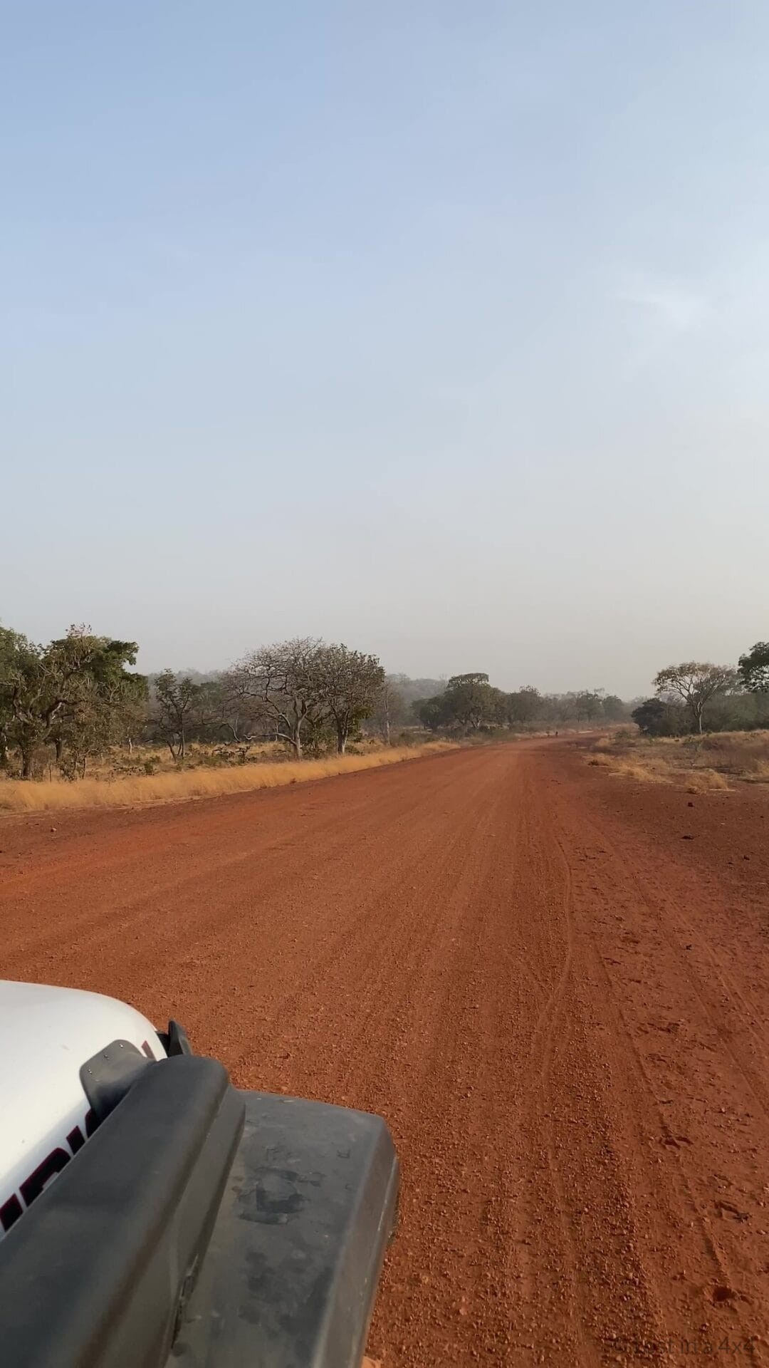 Overland Jeep driving along a red dirt road near Dindefelo in Senegal