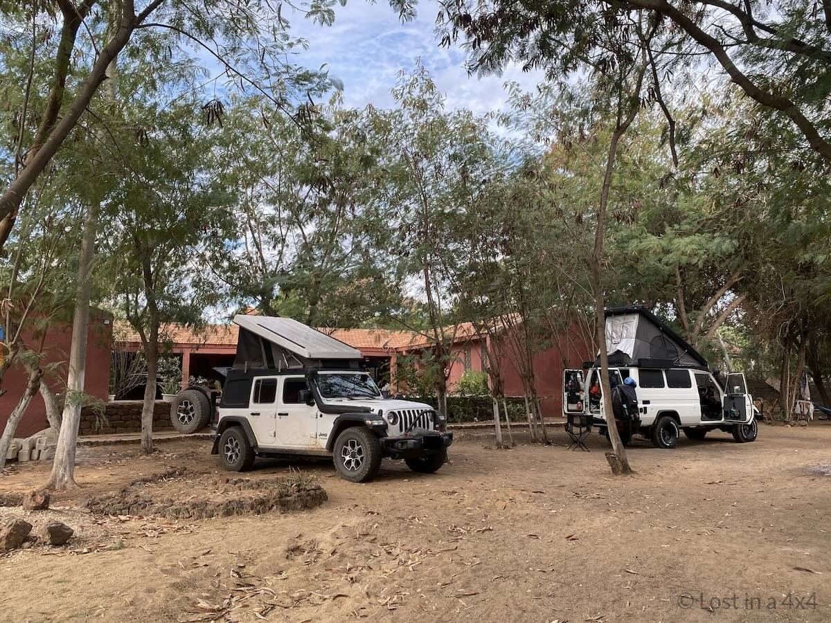 Overland Jeep with Ursa Minor pop up tent set up at Sleeping Camel Camp in Somone Senegal beside another overlander vehicle
