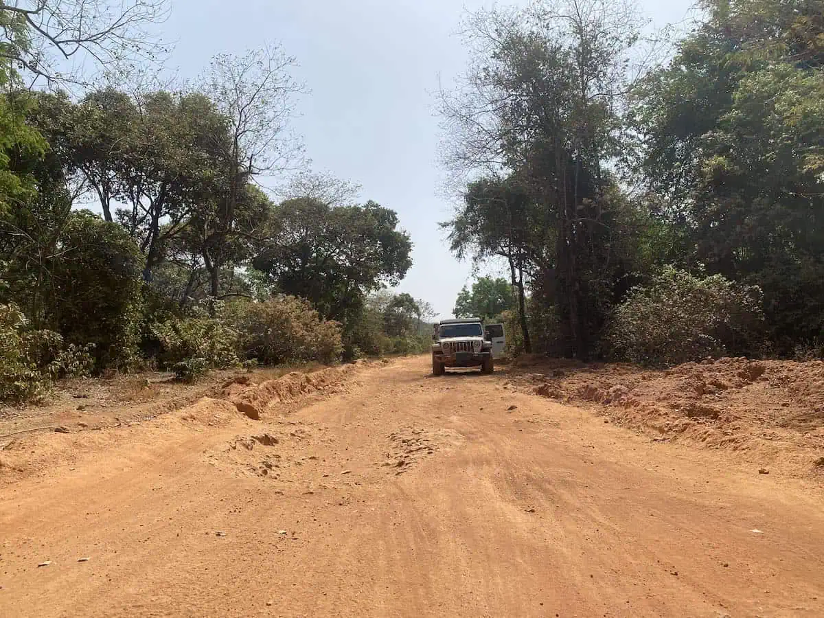 Jeep Wrangler Rubicon parked on side of red dirt road in Guinea mountains during overland Africa trip