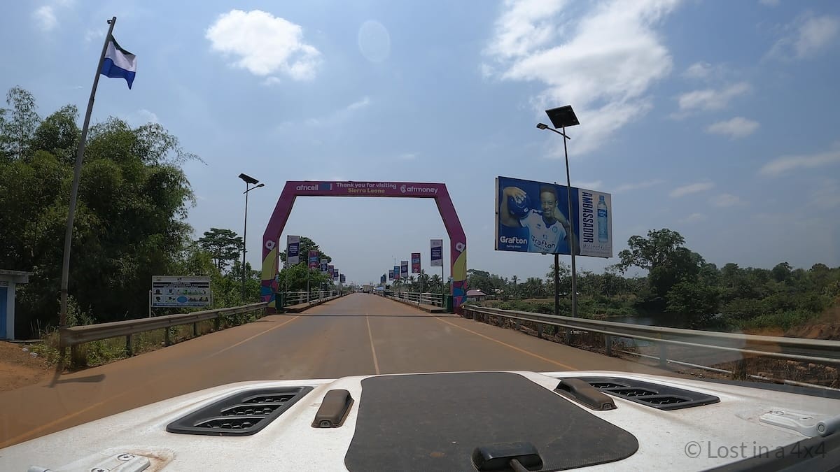 View from inside a Jeep leaving the Sierra Leone border boundary during overland travel into Liberia.