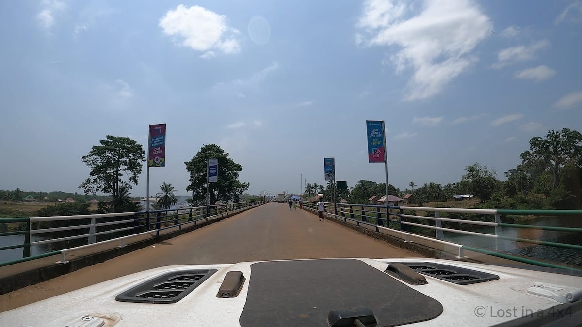 Jeep driving across the “no man’s land” bridge between Sierra Leone and Liberia during overland border crossing.