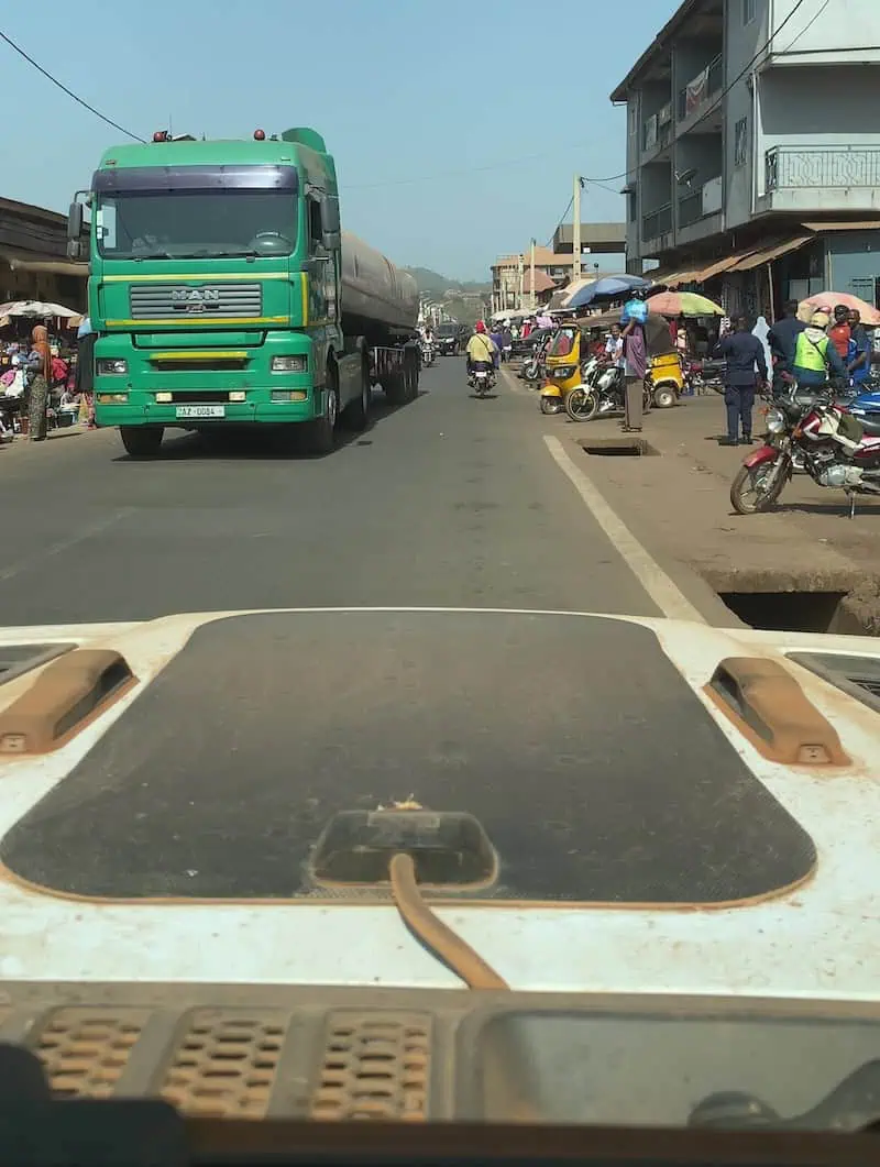 View from Jeep windshield of oncoming semi truck crossing into lane on tarmac road to Conakry Guinea near collision
