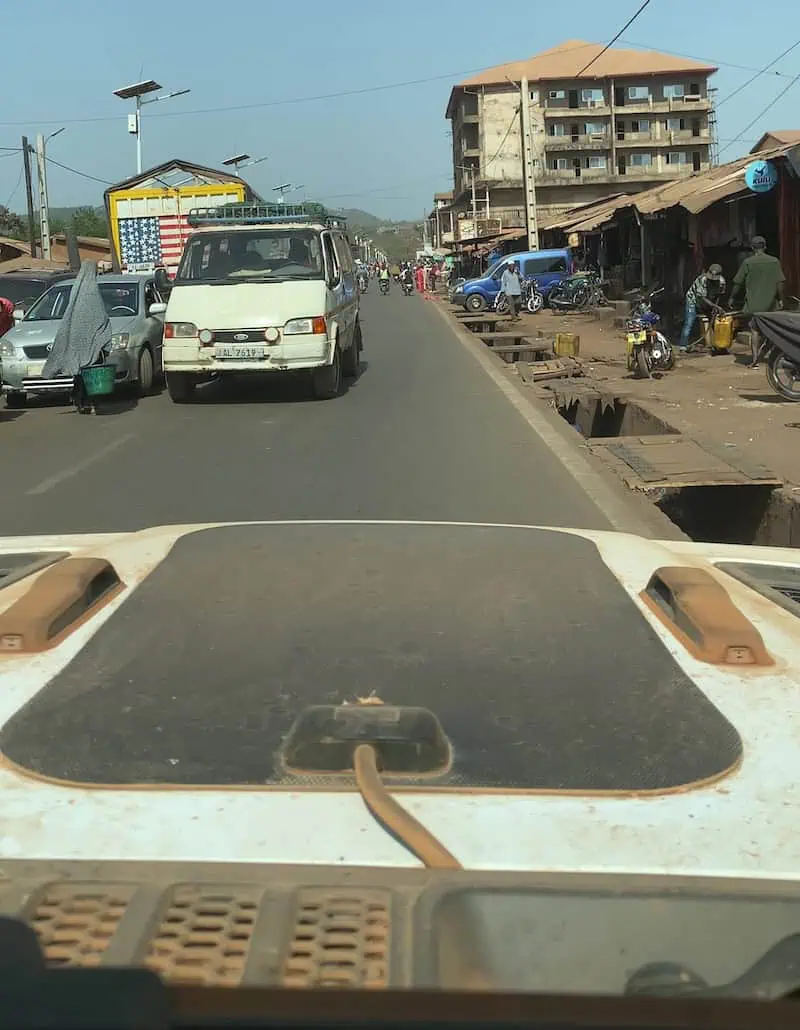 View from Jeep windshield of public minibus crossing into lane on tarmac road to Conakry Guinea,.