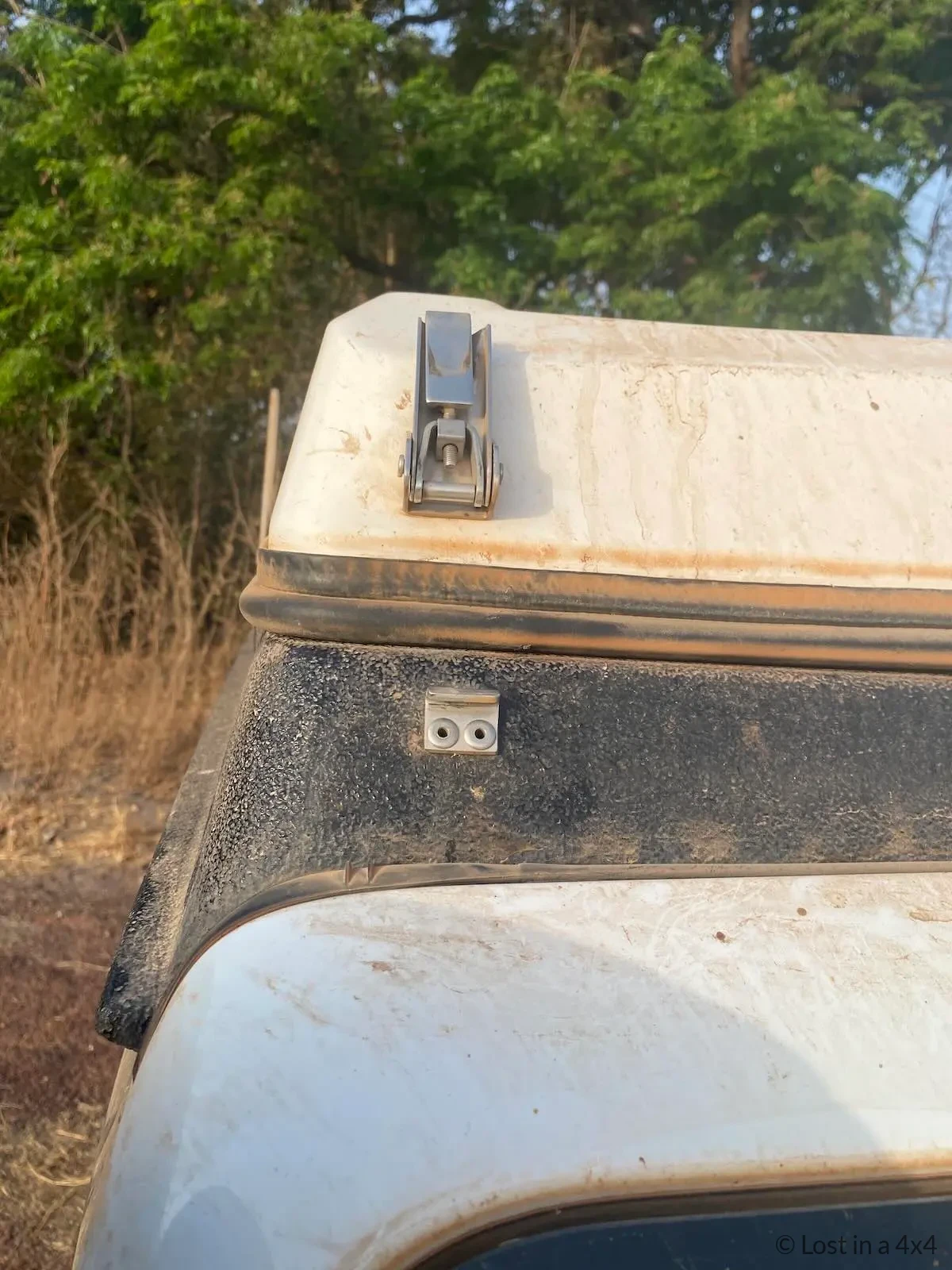 Front locking bracket folded upward against an Ursa Minor pop-top camper before closing the roof.