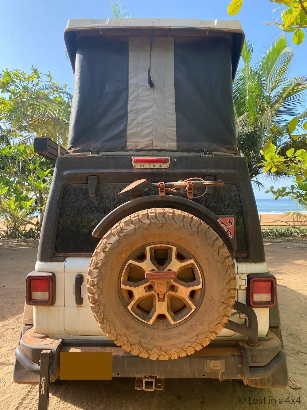 Rear view of Jeep Wrangler with Ursa Minor pop-top camper fully deployed while beach camping in Ivory Coast.