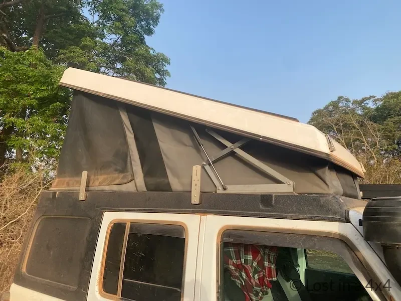Close-up of Ursa Minor pop-top camper side panel after months of full-time travel in Guinea, showing durability with African dust.