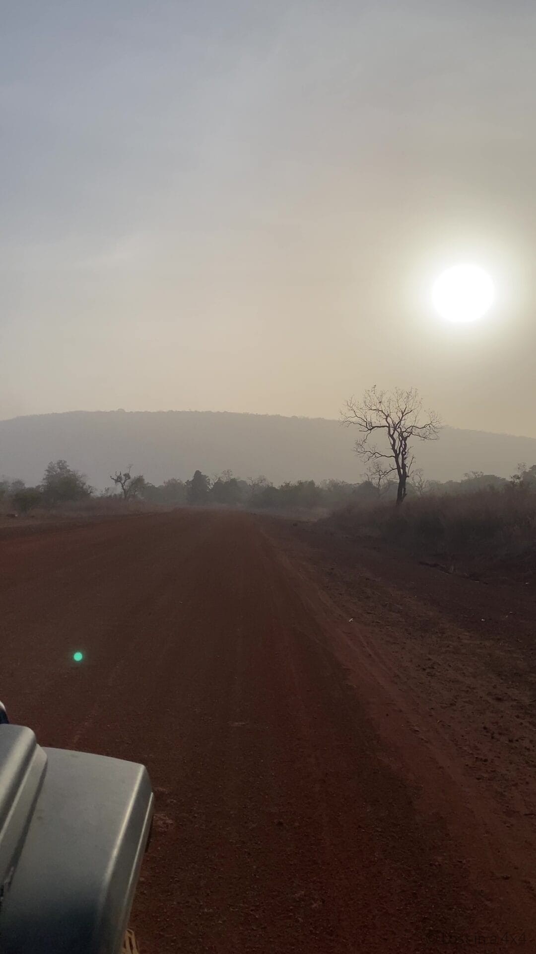 Overland Jeep driving along a red dirt road near Dindefelo in Senegal at sunrise