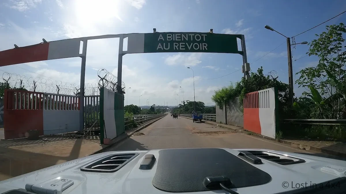 “A bientôt au revoir” sign marking exit from Ivory Coast toward the Ghana border bridge at Noé.