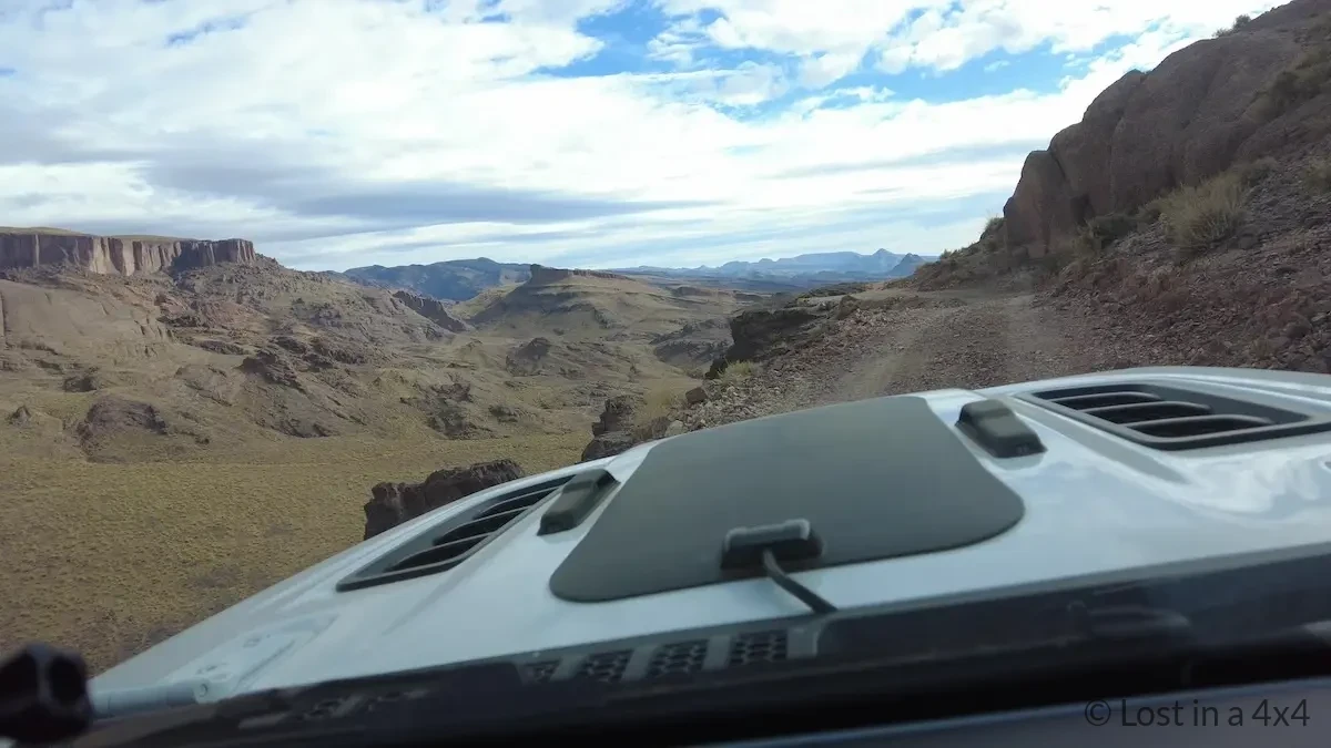 Narrow 4x4 track ahead seen from Jeep dash camera with a cliff drop on the left near Pâte de l'Éléphant in Morocco.