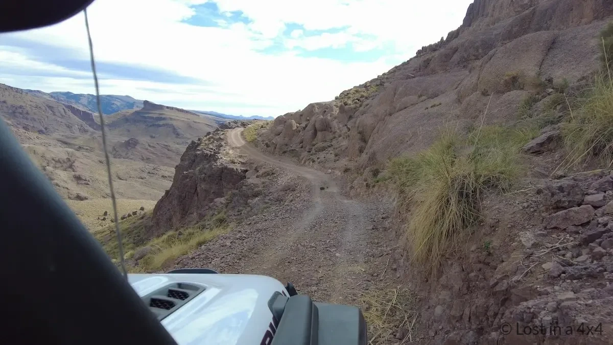 Jeep dash camera view of a narrow mountain track with a cliff edge on the left near Pâte de l'Éléphant in Morocco.